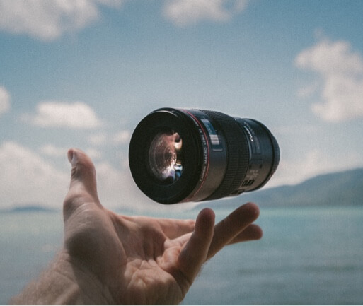 Human hand with a camera lens hovering above it overlooking water